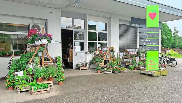 Im Eingangsbereich s Im Eingangsbereich stehen Blumen und Setzlinge zum Verkauf. Trotz des Schildes erinnert der Hofladen an seine frühere Bestimmung als Garage. Von Vorteil ist die grosszügig bemessene Parkplatzzone.