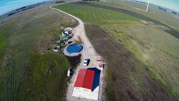 Wohnhaus, Container Wohnhaus, Container und Wasserreservoir sowie im Hintergrund die Linien mit den ersten Pekanbäumen.